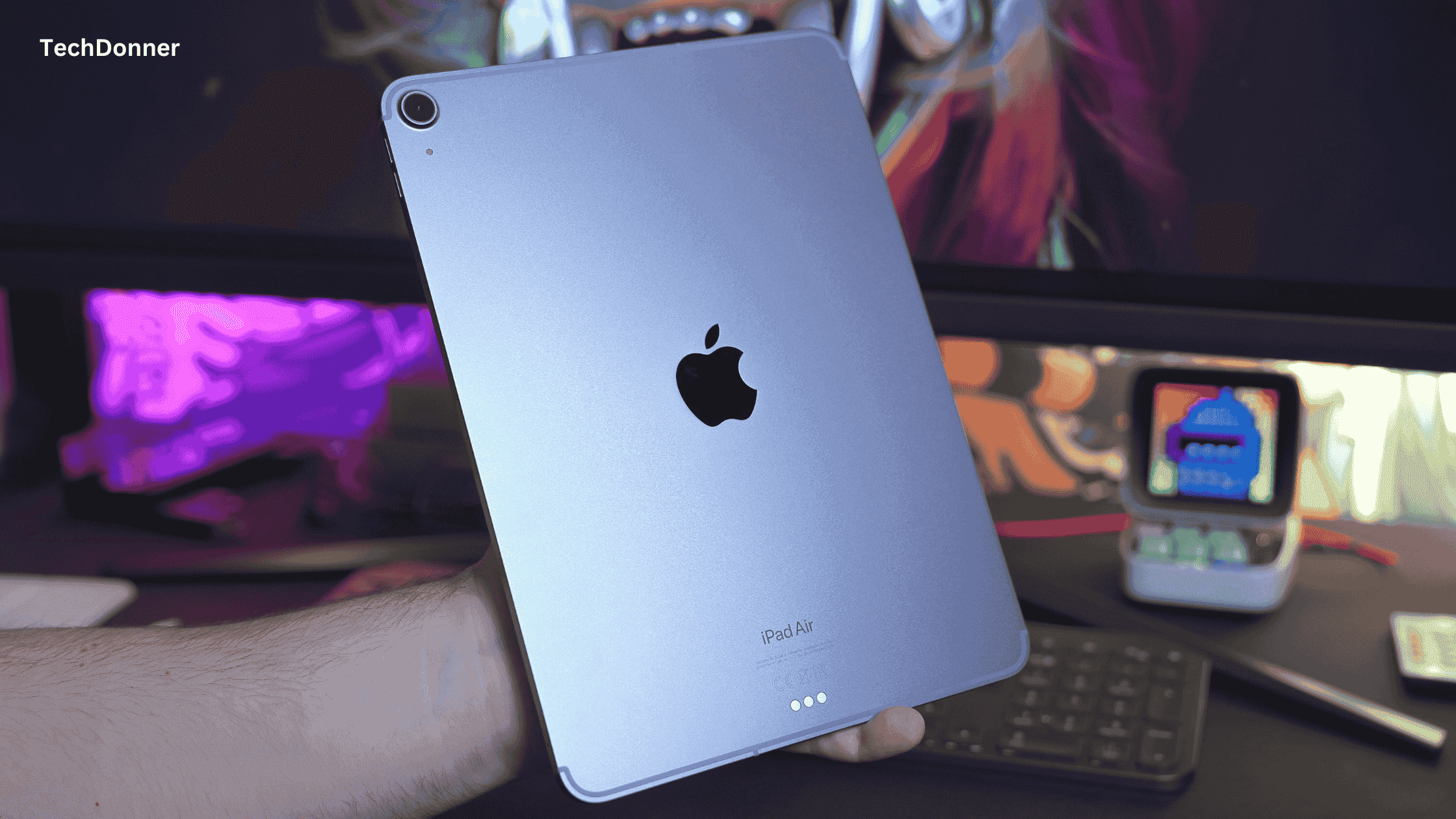 holding an iPad Air with gaming setup in background